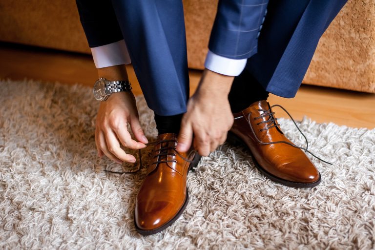 Is your protection still the right fit? A man ties up his shoelaces on his brown shoes in the room.